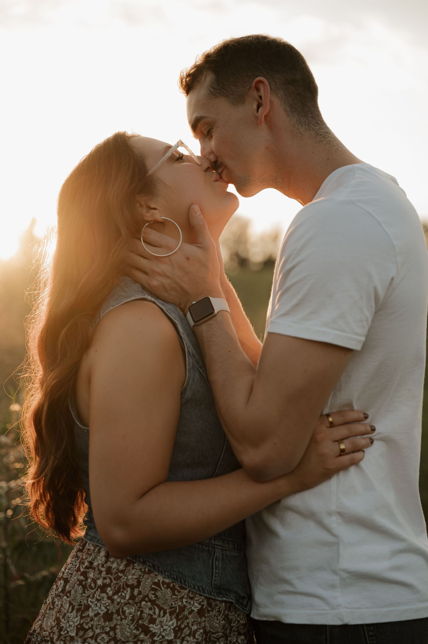 Couple about to kiss in a sun-drenched field during warm golden hour light.
