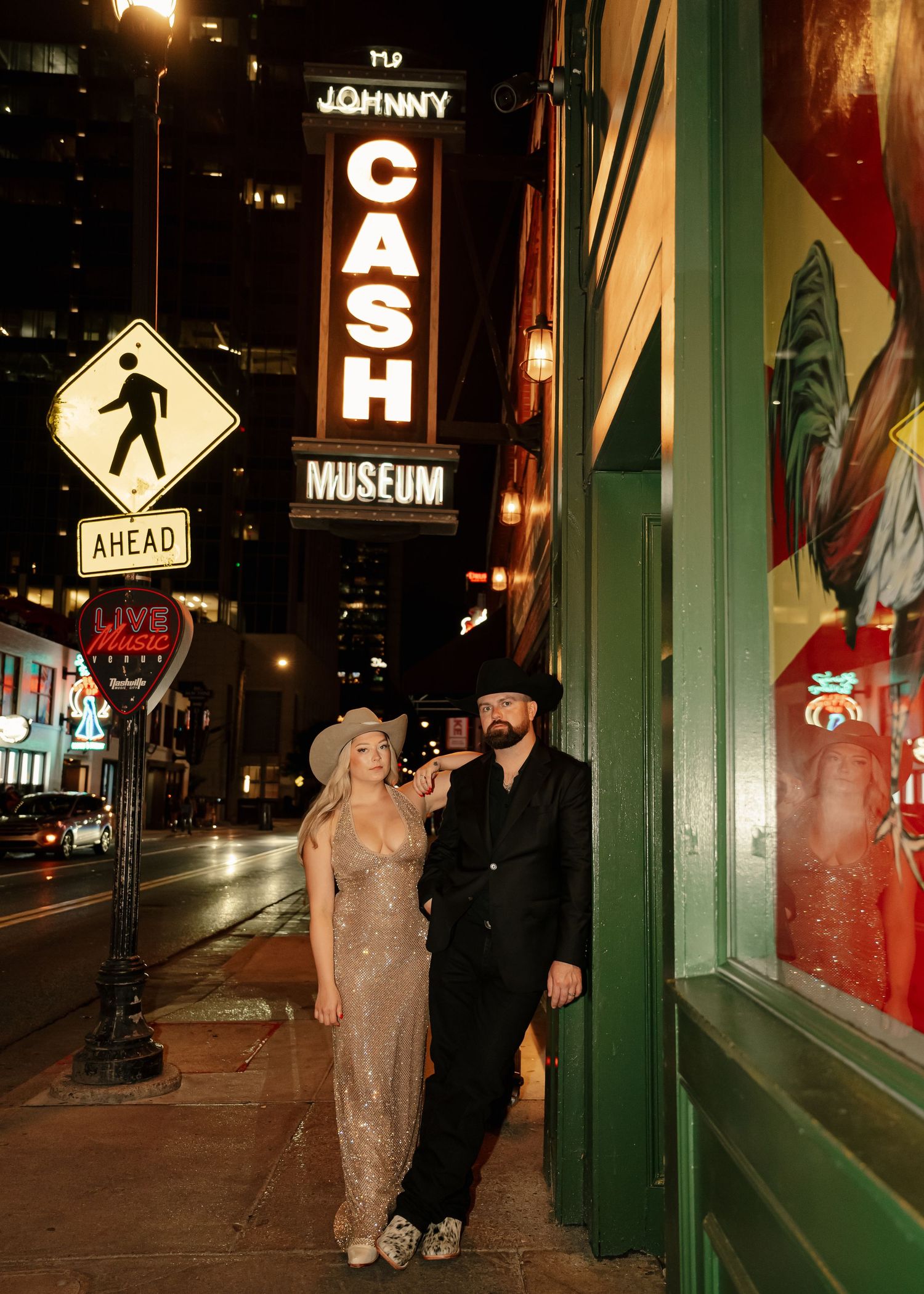 Couple posing at night outside the Johnny Cash Museum in Nashville, Tennessee, dressed in elegant country-style attire.