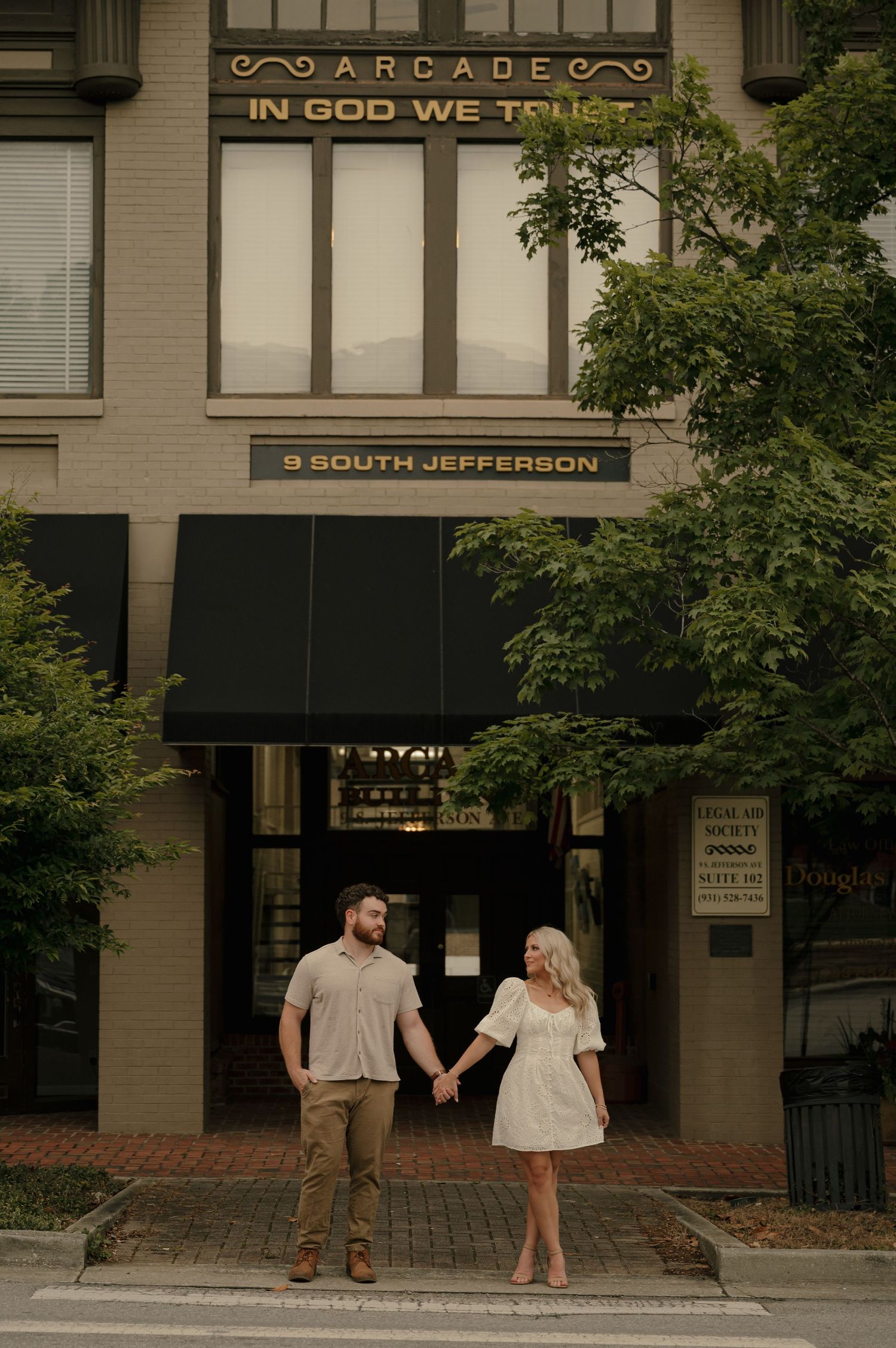 Couple holding hands outside the Arcade building at 9 South Jefferson on a sunny day.