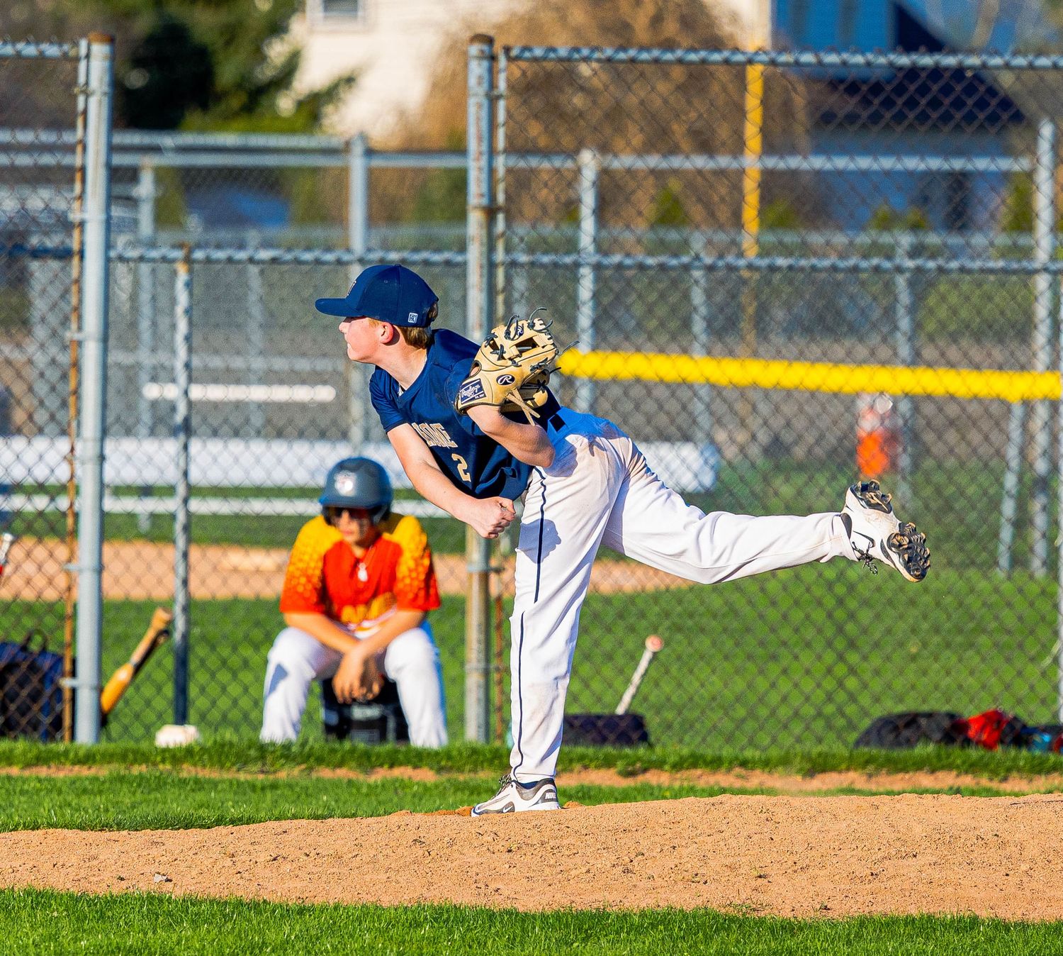 Baseball pitcher on a dirt mound follows through with dramatic throwing motion during a game.