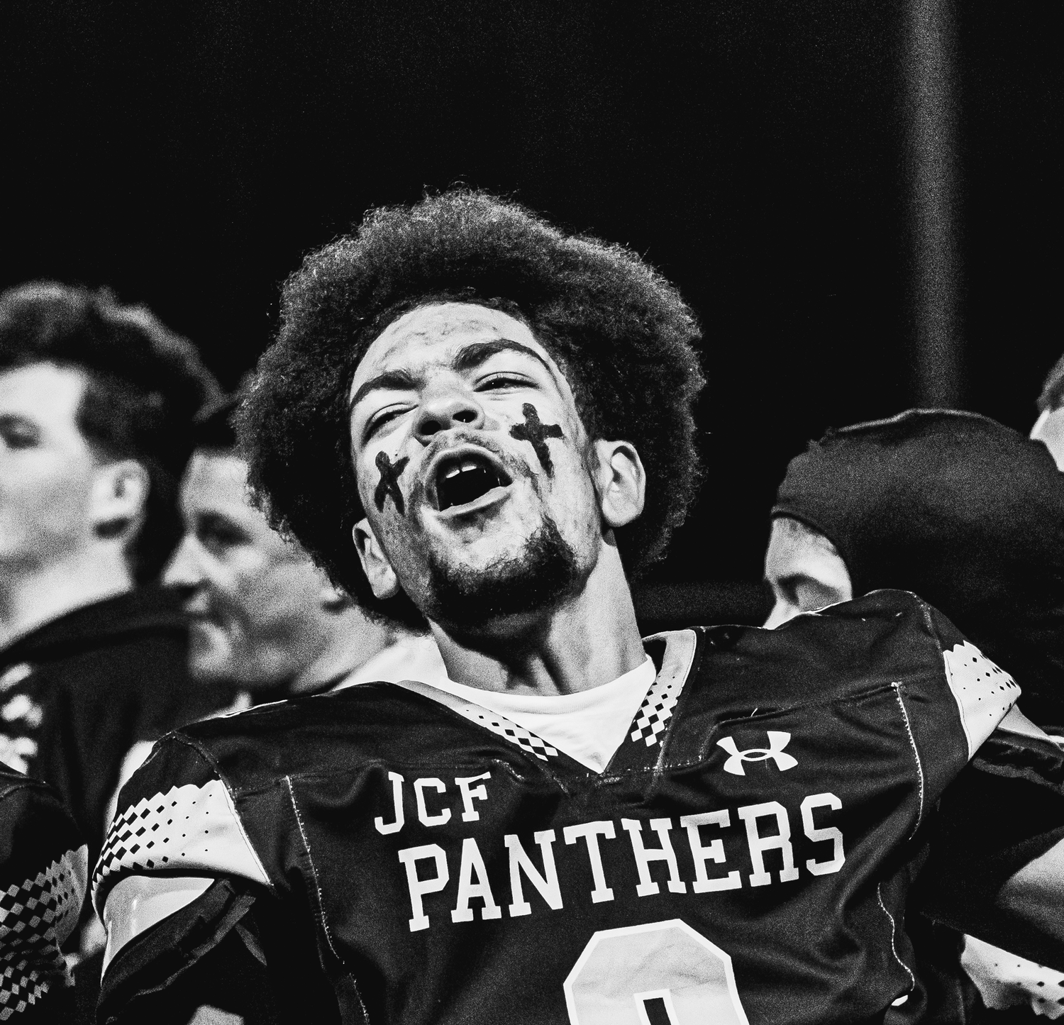 A JCF Panthers football player celebrates emotionally on the field in a black and white photo.