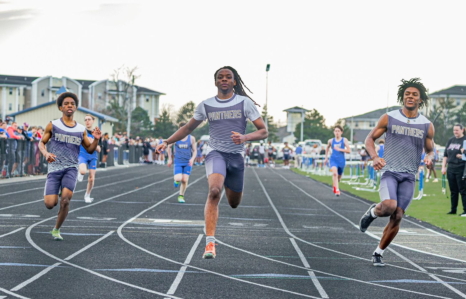 Athletes compete in a sprint race on an outdoor track during a high school track and field meet.