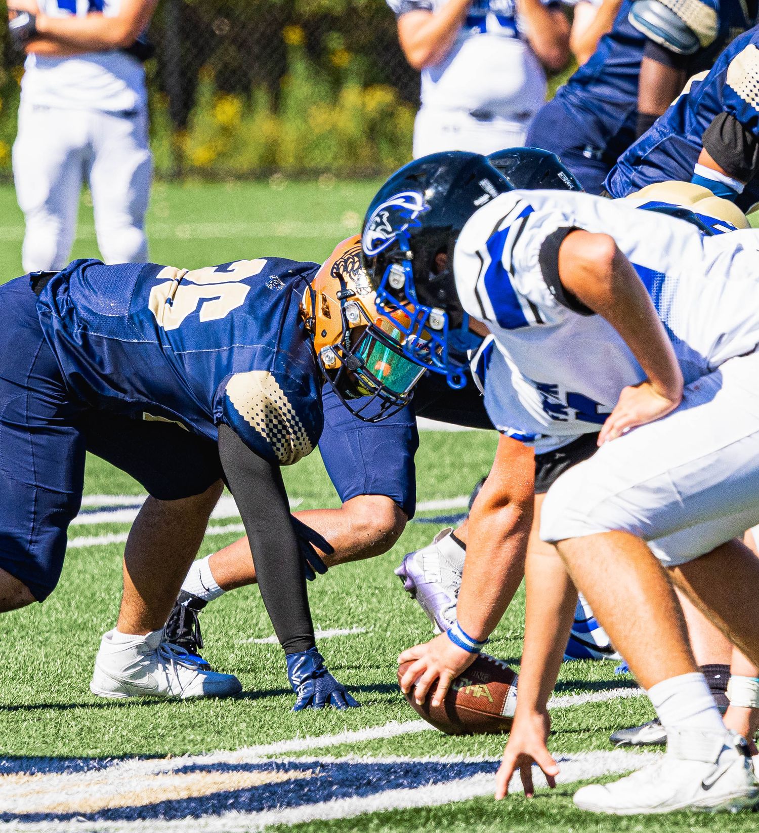 High school football players face off at the line of scrimmage during an intense daytime game.