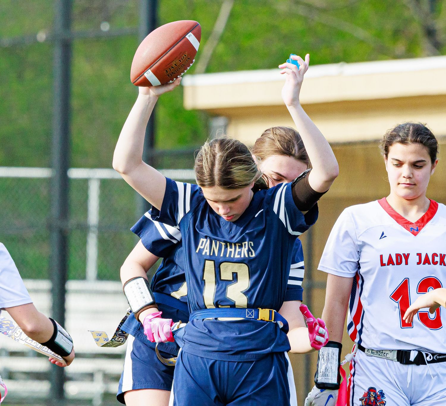 Panthers player #13 celebrates with teammate during a girls flag football game on the field.