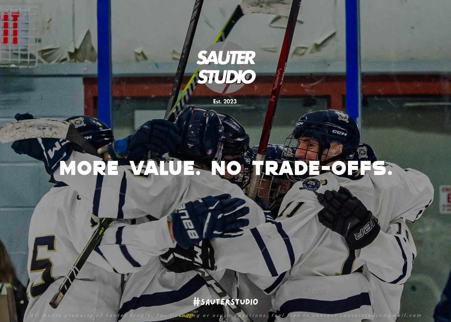 Hockey players in white and navy jerseys huddle together during a game at Sauter Studio.