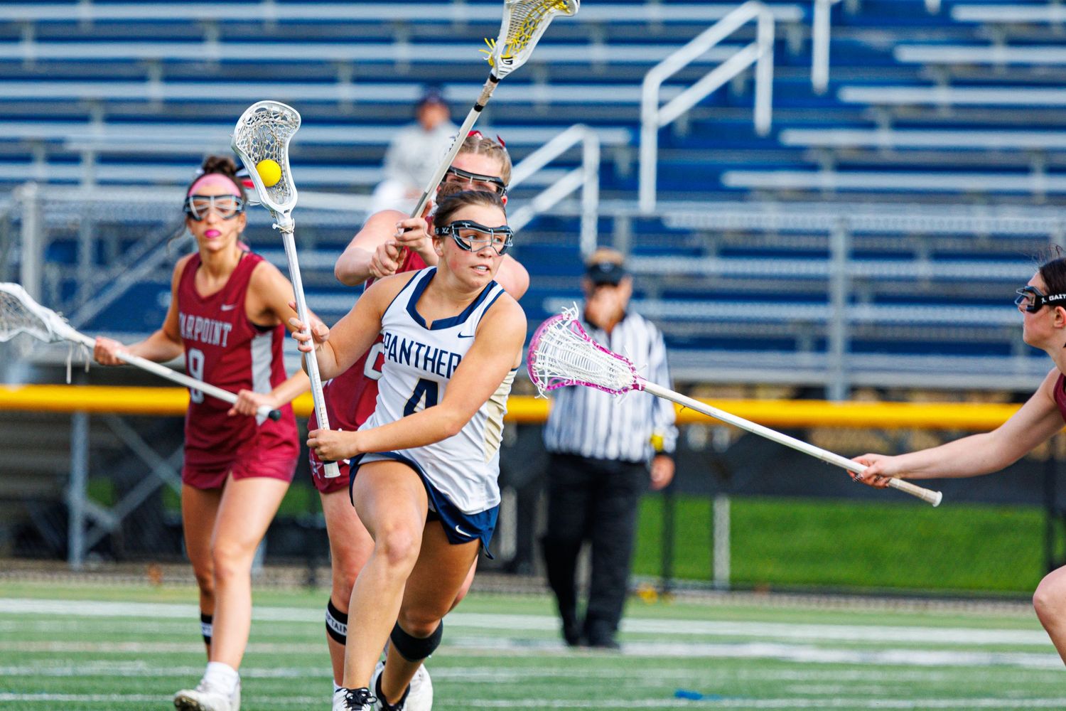 Panthers female lacrosse player drives with the ball during a competitive high school lacrosse game.