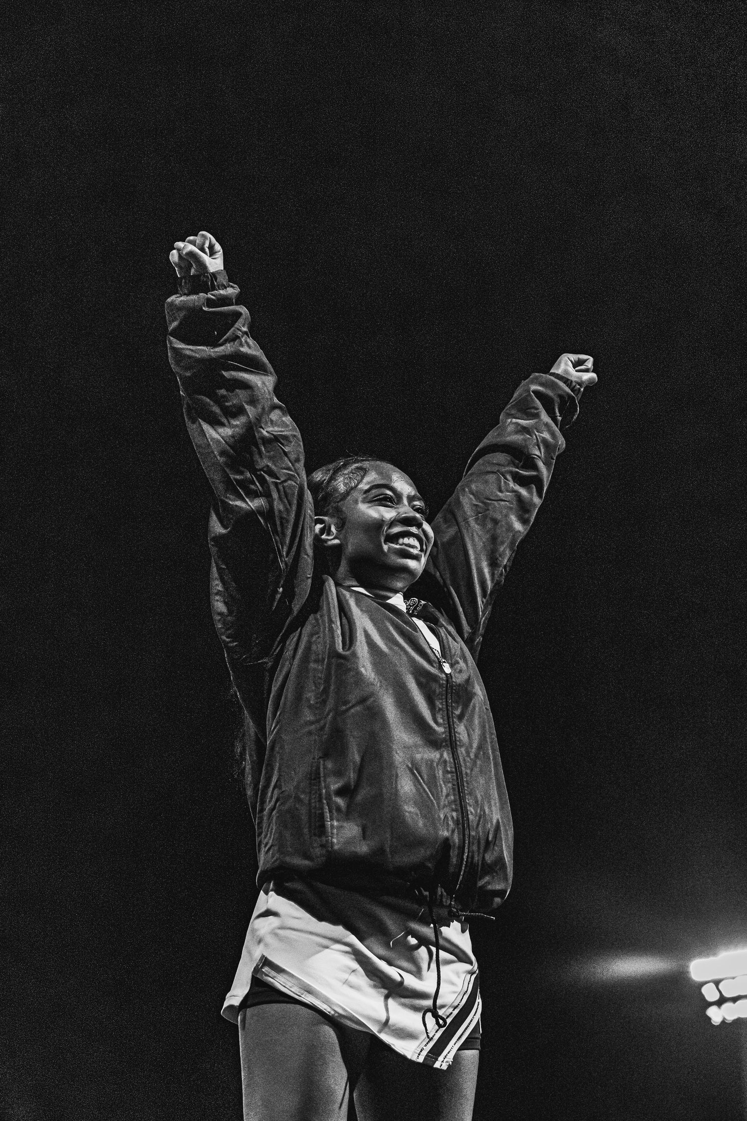 Black and white photo of a joyful athlete raising both arms in victory celebration.