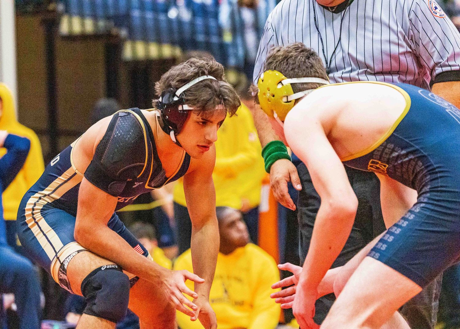 Two wrestlers in intense face-off stance during competitive wrestling match.