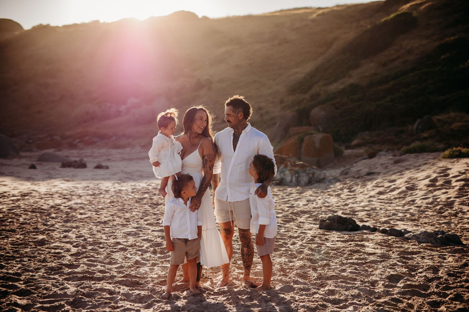Family standing on a beach in golden sunshine with cliffs behind.  Adelaide family and lifestyle photographer