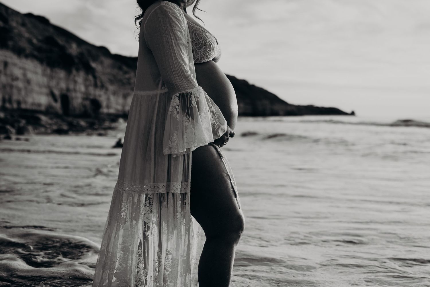 Artistic photo of baby bump captured at shoreline during golden hour – Raised by Water Photography