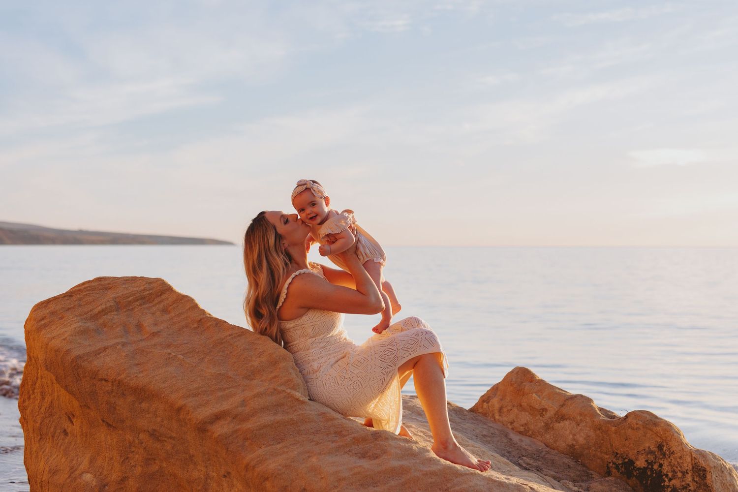 Mum cradling baby by the ocean during golden hour – South Australian beach photography