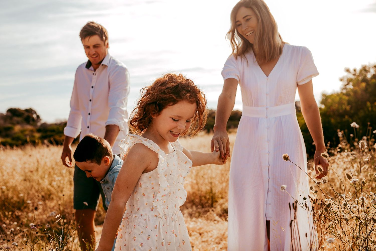 Family photo of mother and child holding hands in open field – Raised by Water Photography