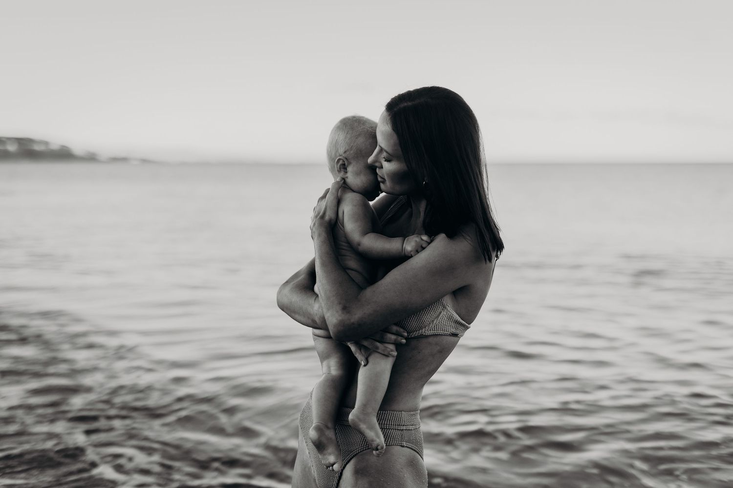 Mum embracing child standing in the ocean.  Adelaide family and motherhood photographer, South Australia.  Raised by Water Photography