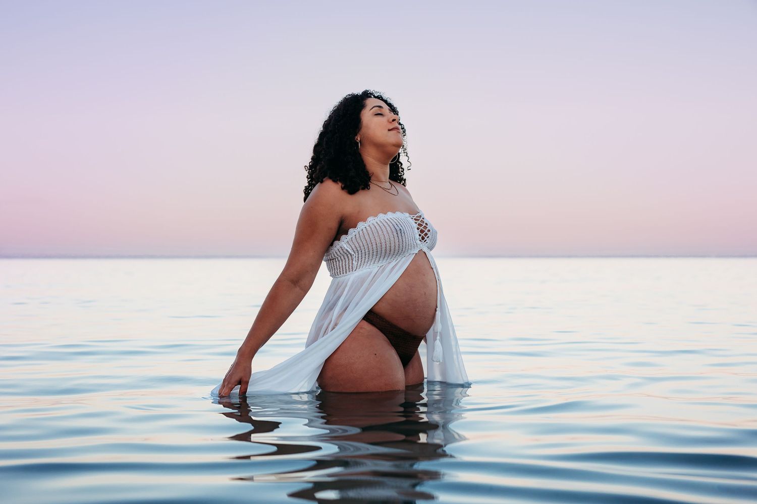 Mother-to-be embracing bump in the ocean during golden hour – South Australian beach photography