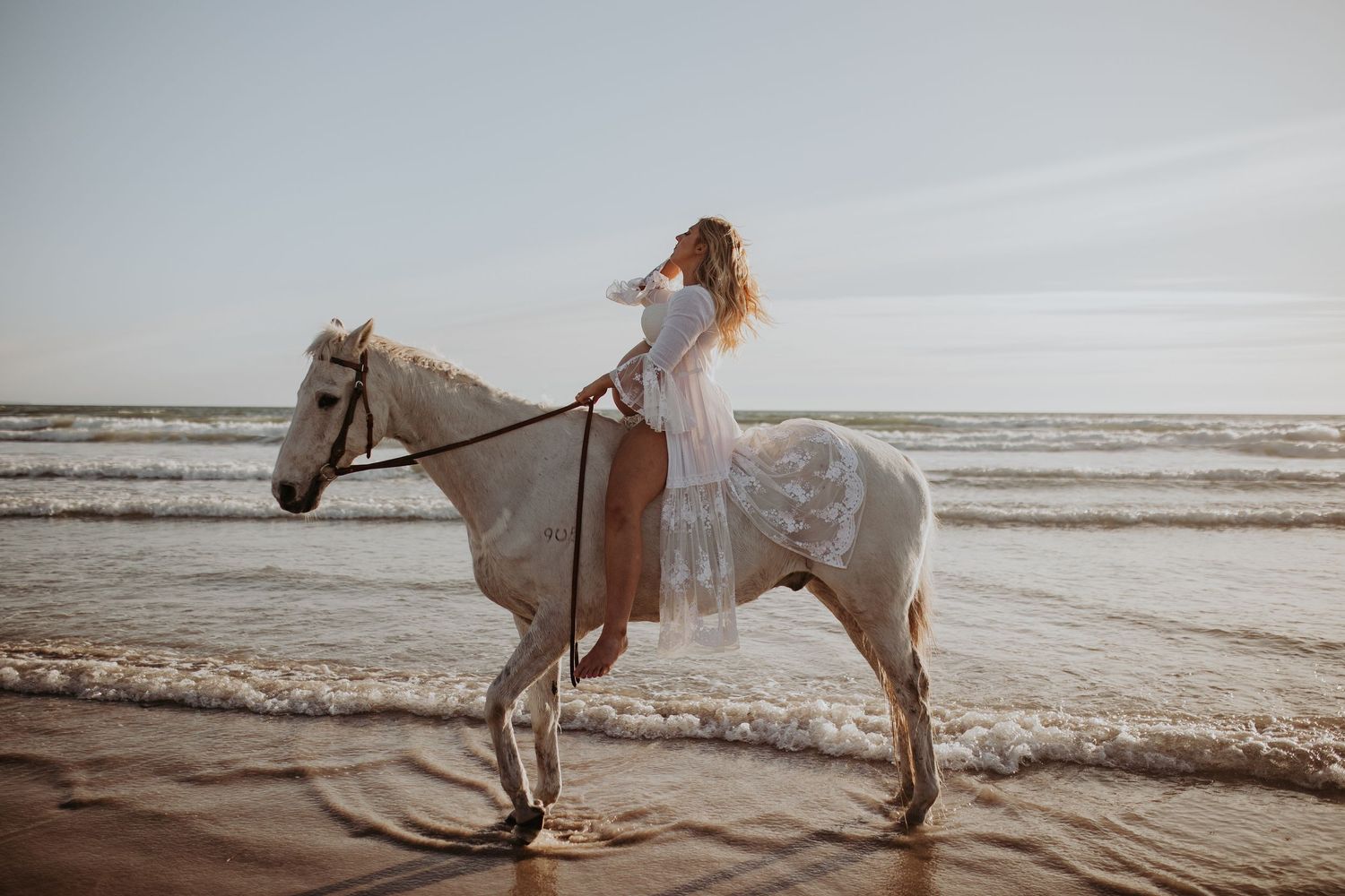 Pregnant lady sitting on a horse at the beach in Adelaide, South Australia
