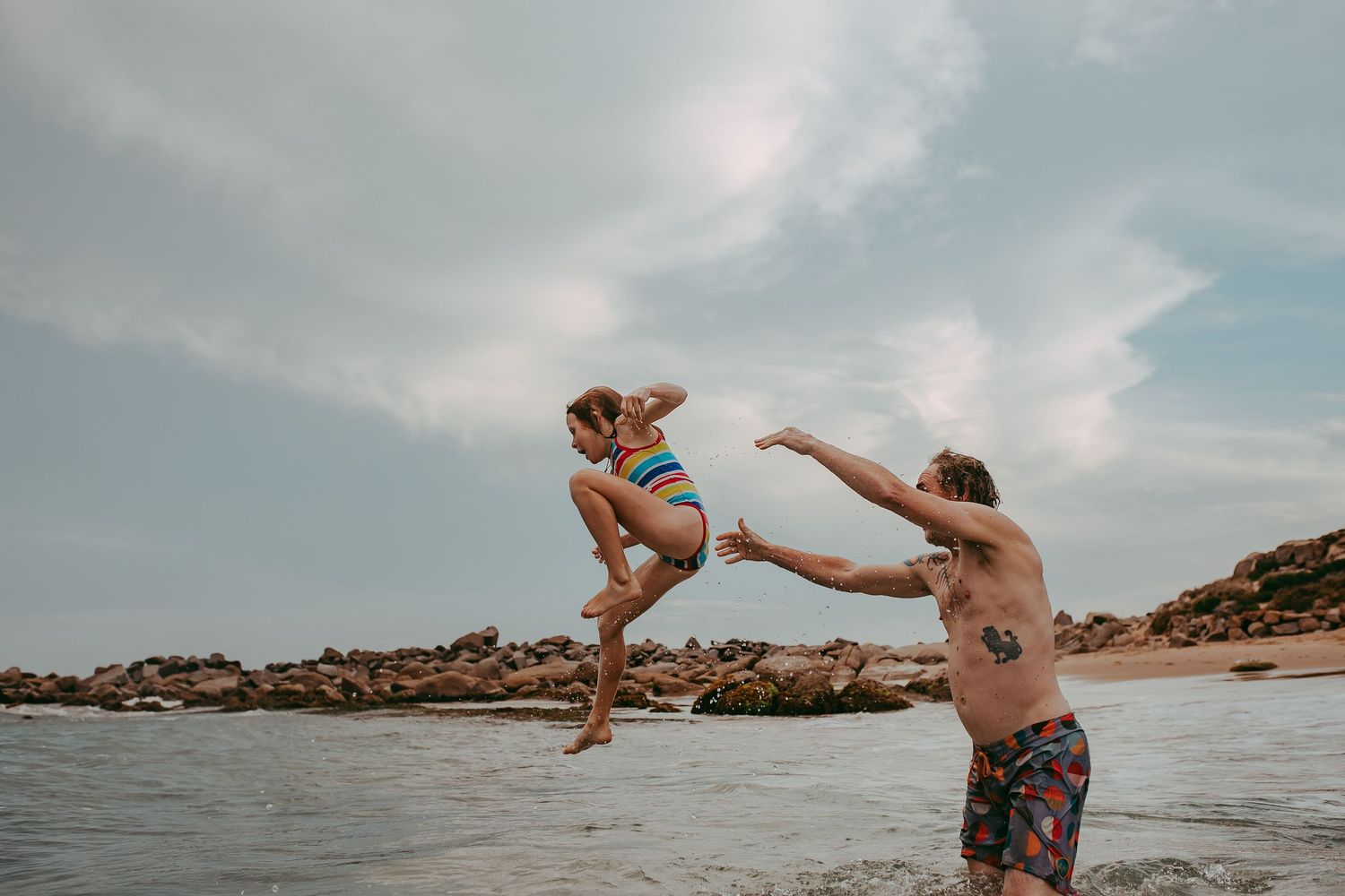 Fun image of Dad throwing his daughter into the ocean.  Adelaide family lifestyle photographer - Raised by Water Photography
