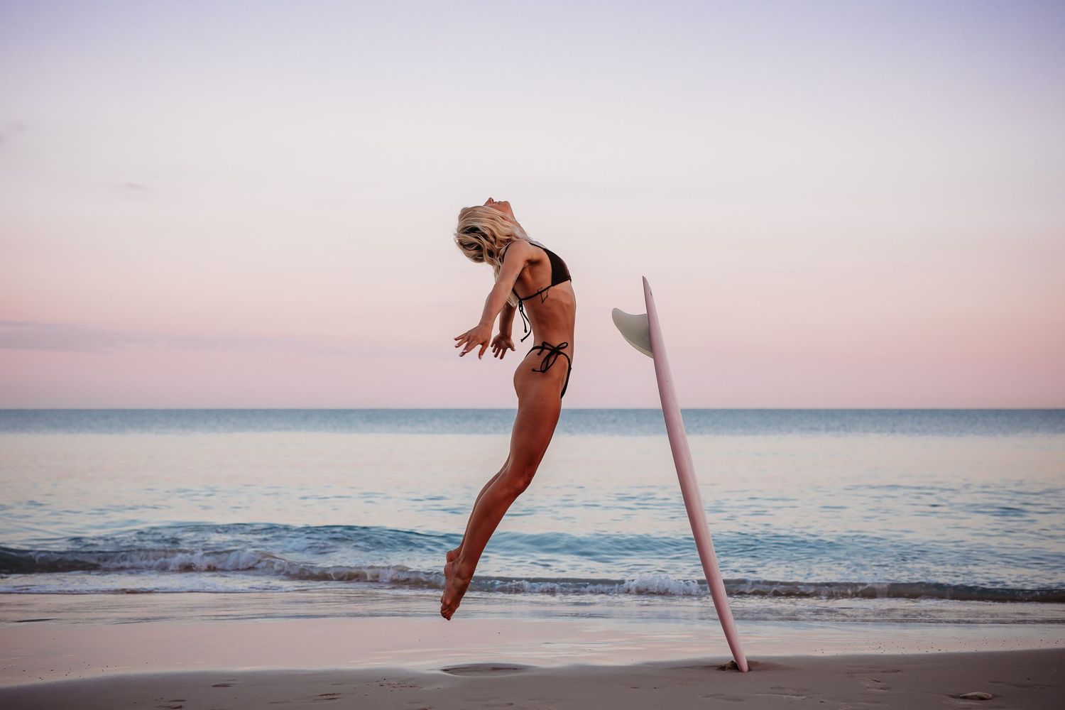 lady dancing at sunrise with a surfboard  at the beach in Adelaide, South Australia - Raised by Water Photography - She and the Wild Sea