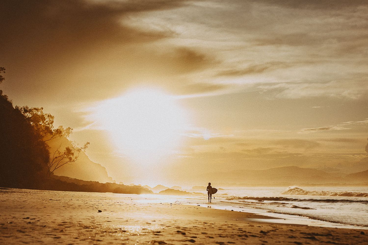 Surfer standing in golden light on the beach - Raised by Water Photography
