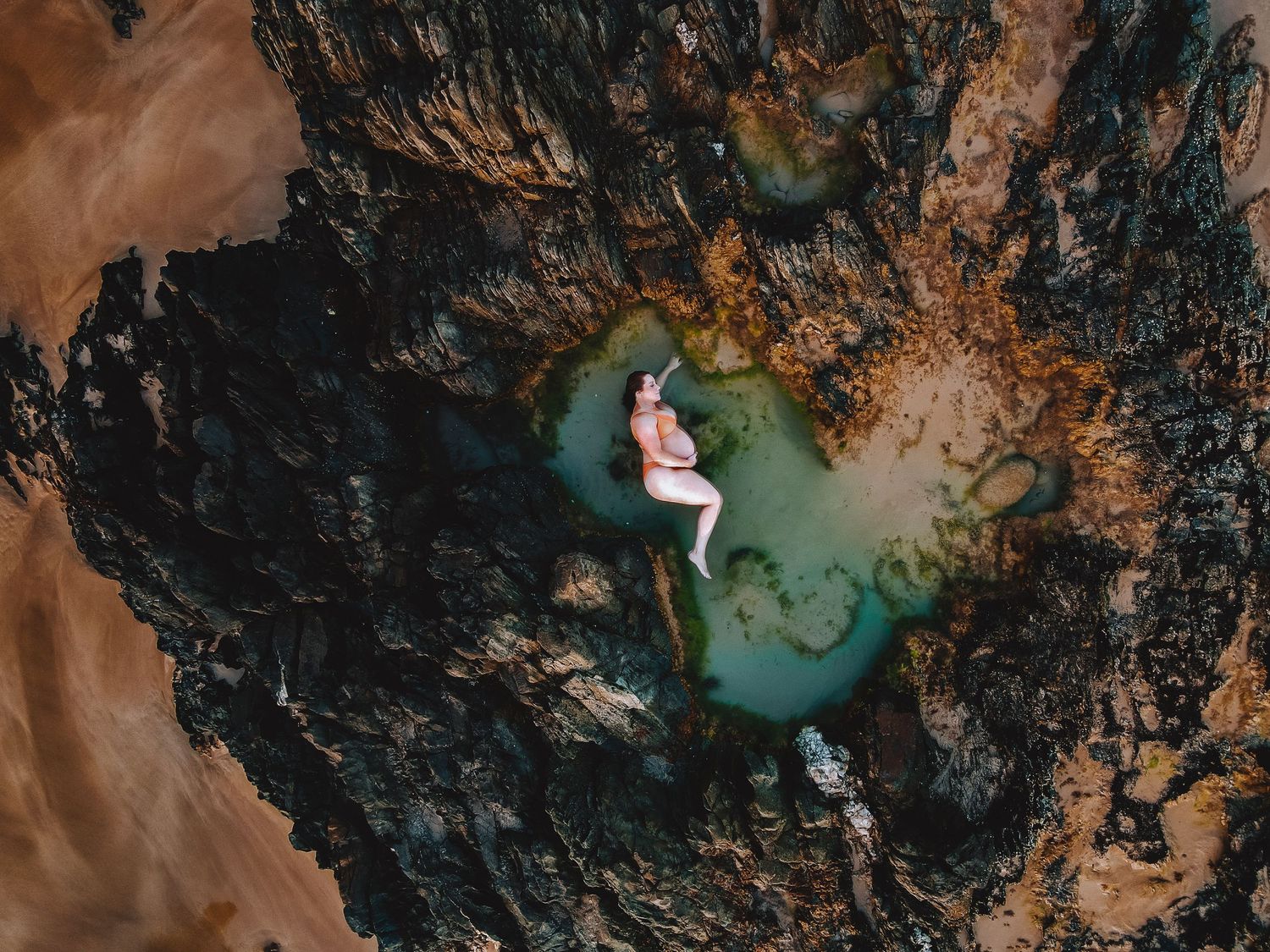 Pregnant mum lying peacefully in love heart-shaped rock pool by the ocean – Raised by Water Photography, Adelaide