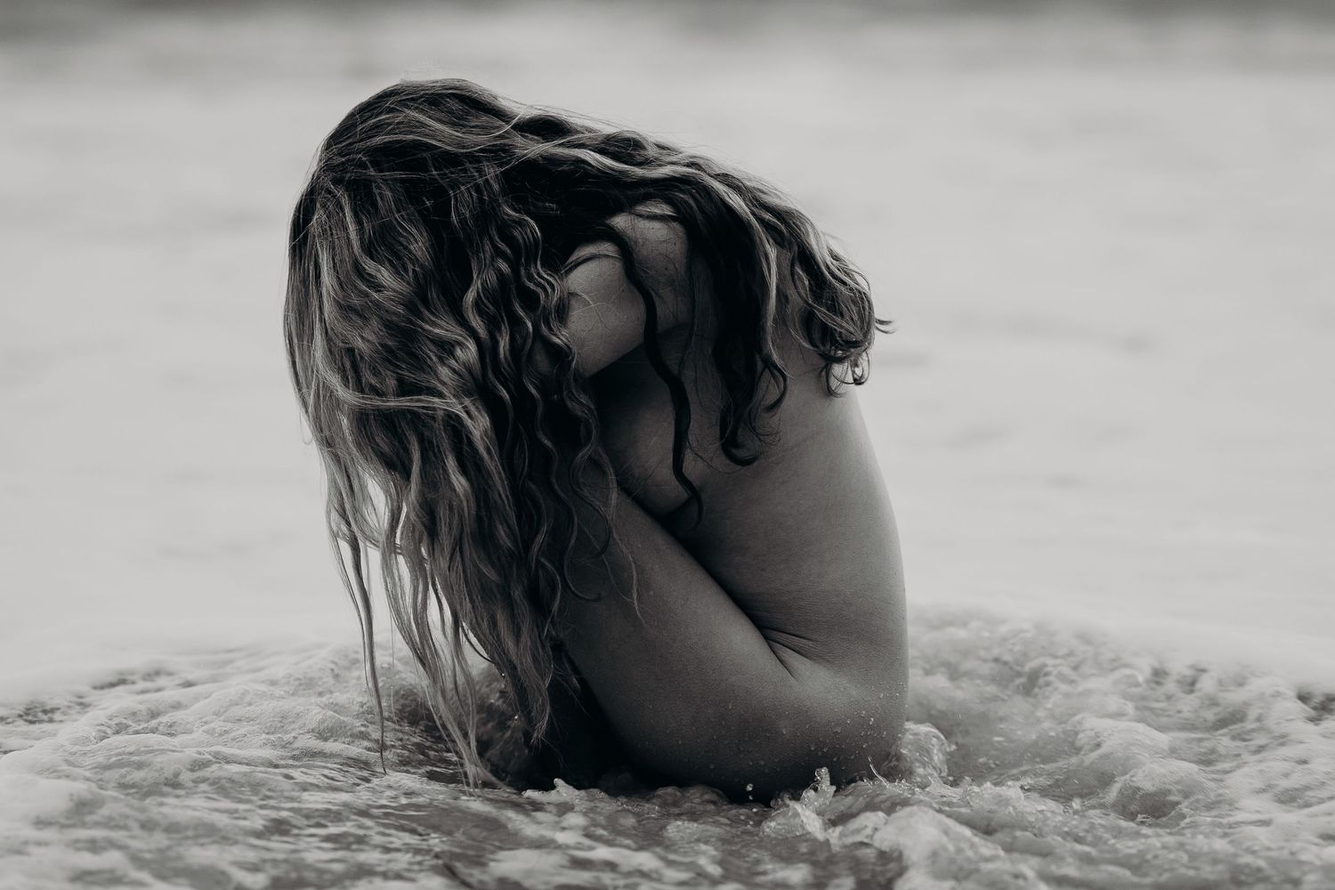 Serene image of woman sitting in calm ocean water, hair draped over body, hands holding knees – South Australia natural photography