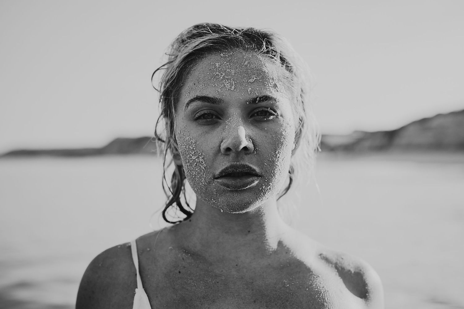 close up of woman's face covered in sand. Adelaide portrait photographer
