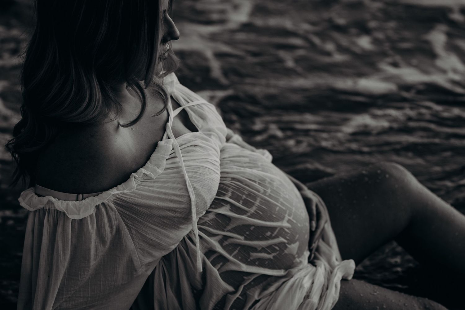 Close up pregnant belly sitting in the shallow water.  Adelaide maternity photographer