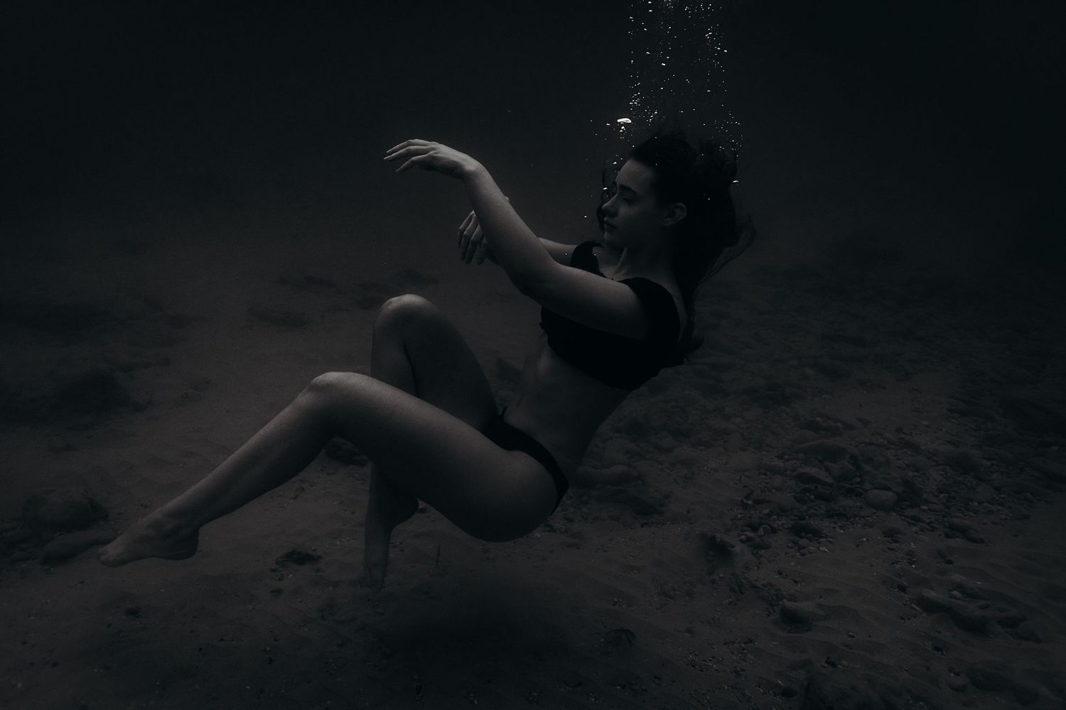 Woman peacefully floating underwater, soft light filtering through ocean in Adelaide, South Australia