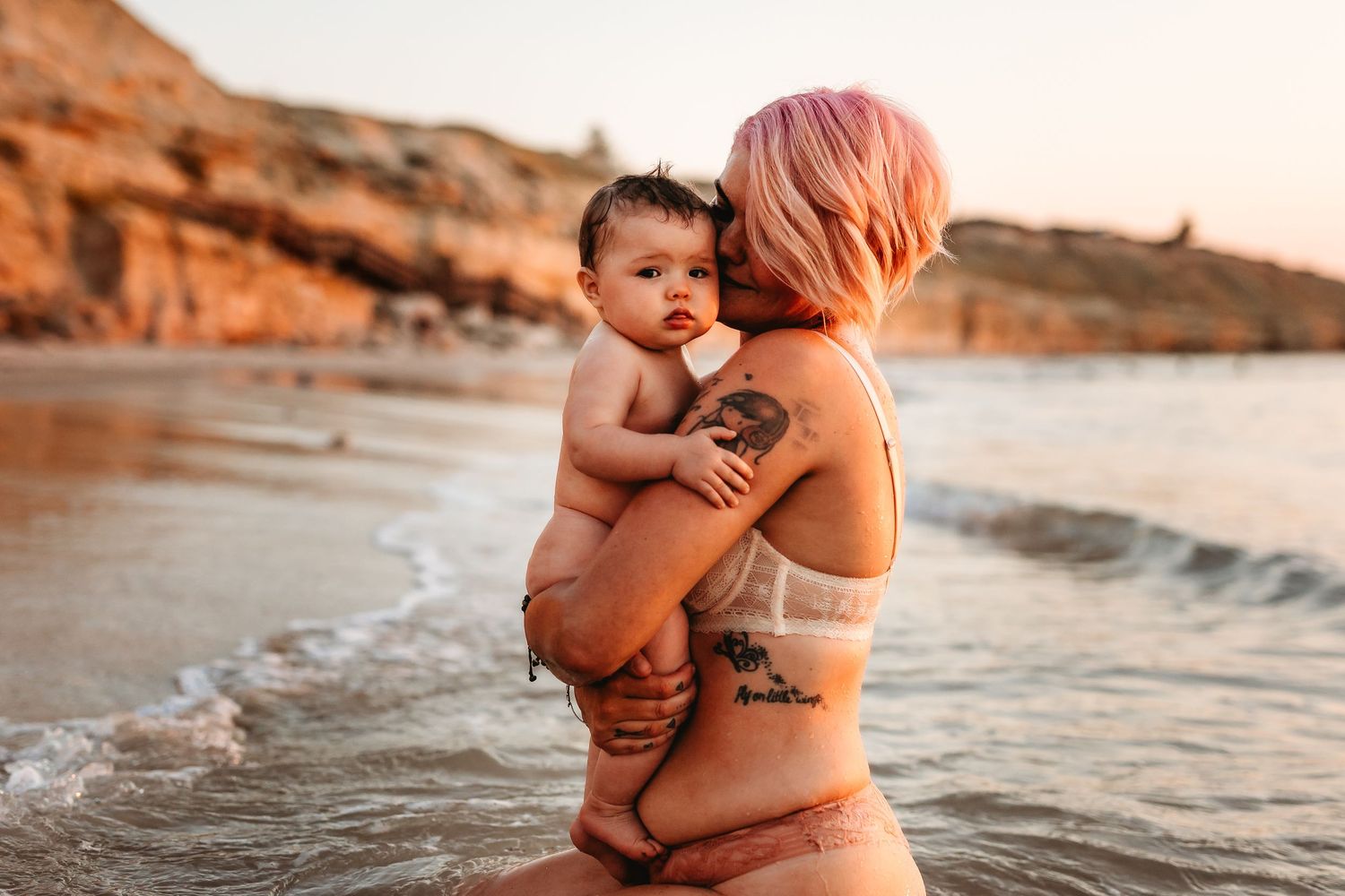 Mother kissing baby with sea breeze and sunset in the background – Adelaide, South Australia