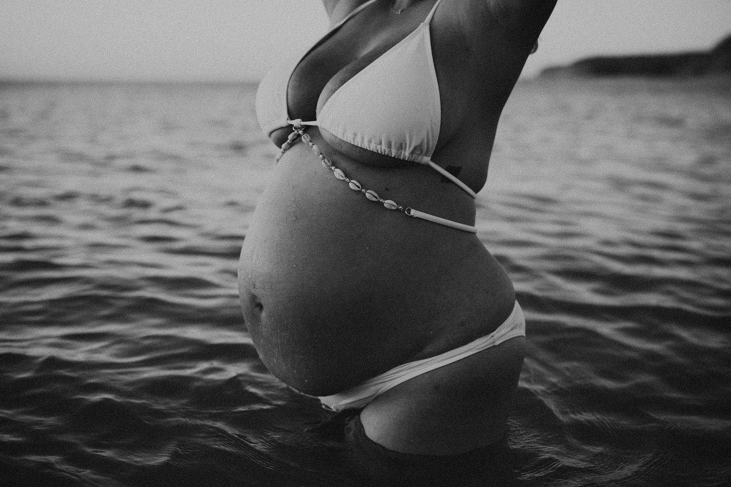 Minimalist black and white image focusing on curves of pregnant belly – South Australia