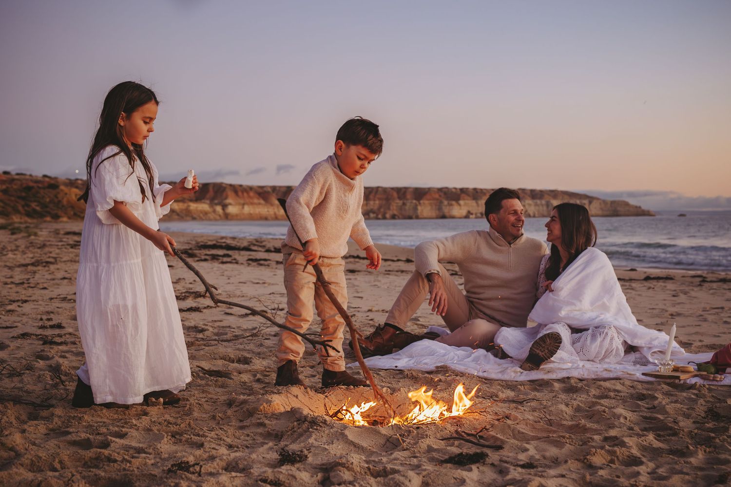 Family standing on beach in front of bonfire roasting marshmallows. Adelaide family lifestyle photographer