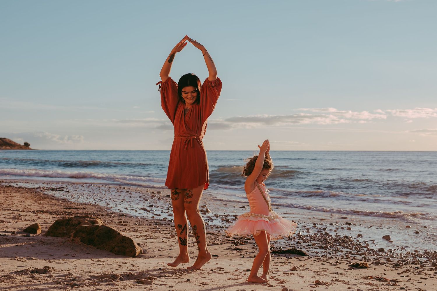 Candid beach moment of mum and daughter twirling together – Raised by Water Photography