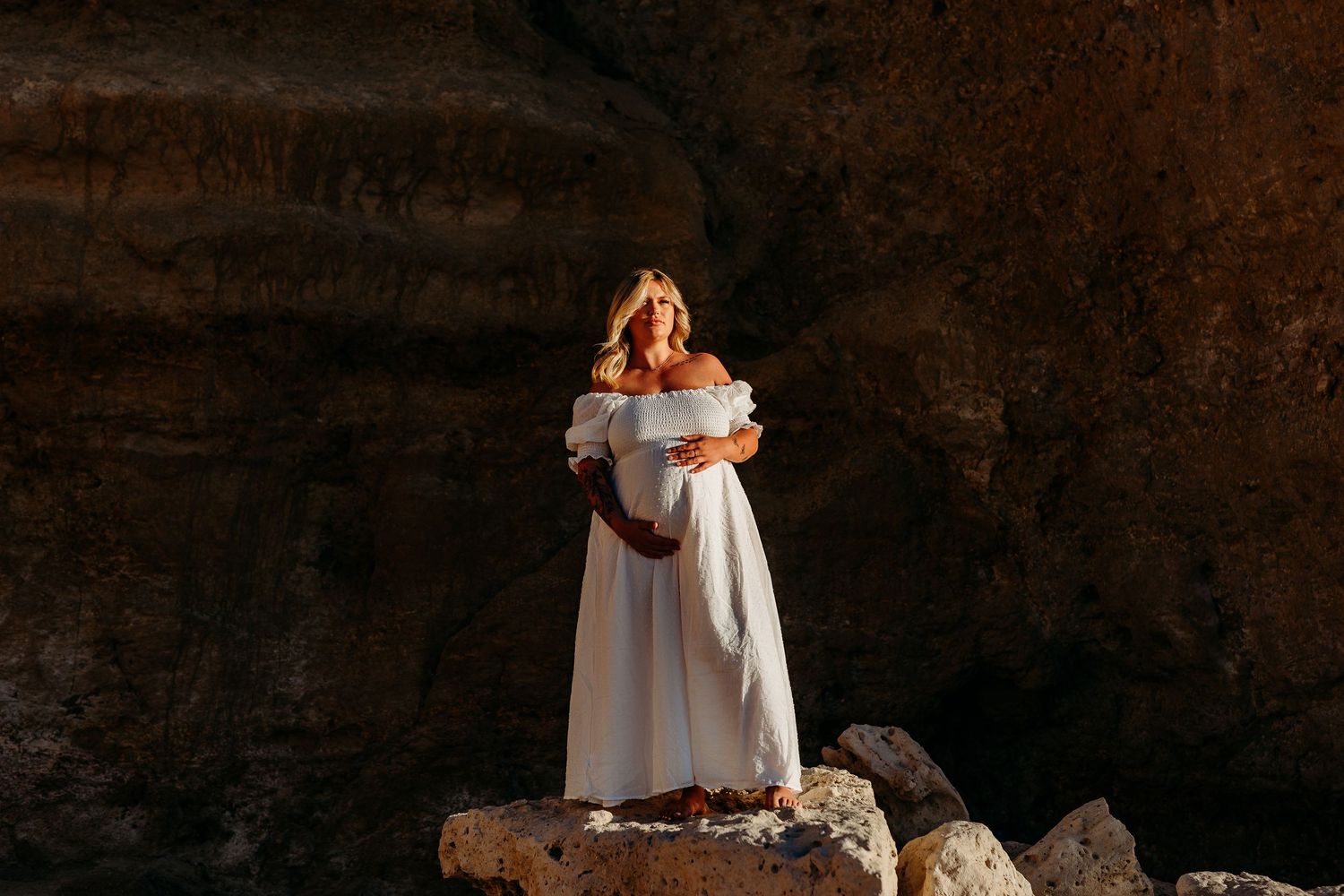 Pregnant lady embracing belly standing on a rock at the beach in Fleurieu peninsula - Adelaide maternity photographer