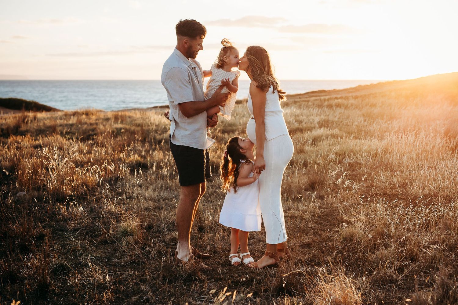 Pregnant mother with family in sunlit field – Adelaide lifestyle maternity session