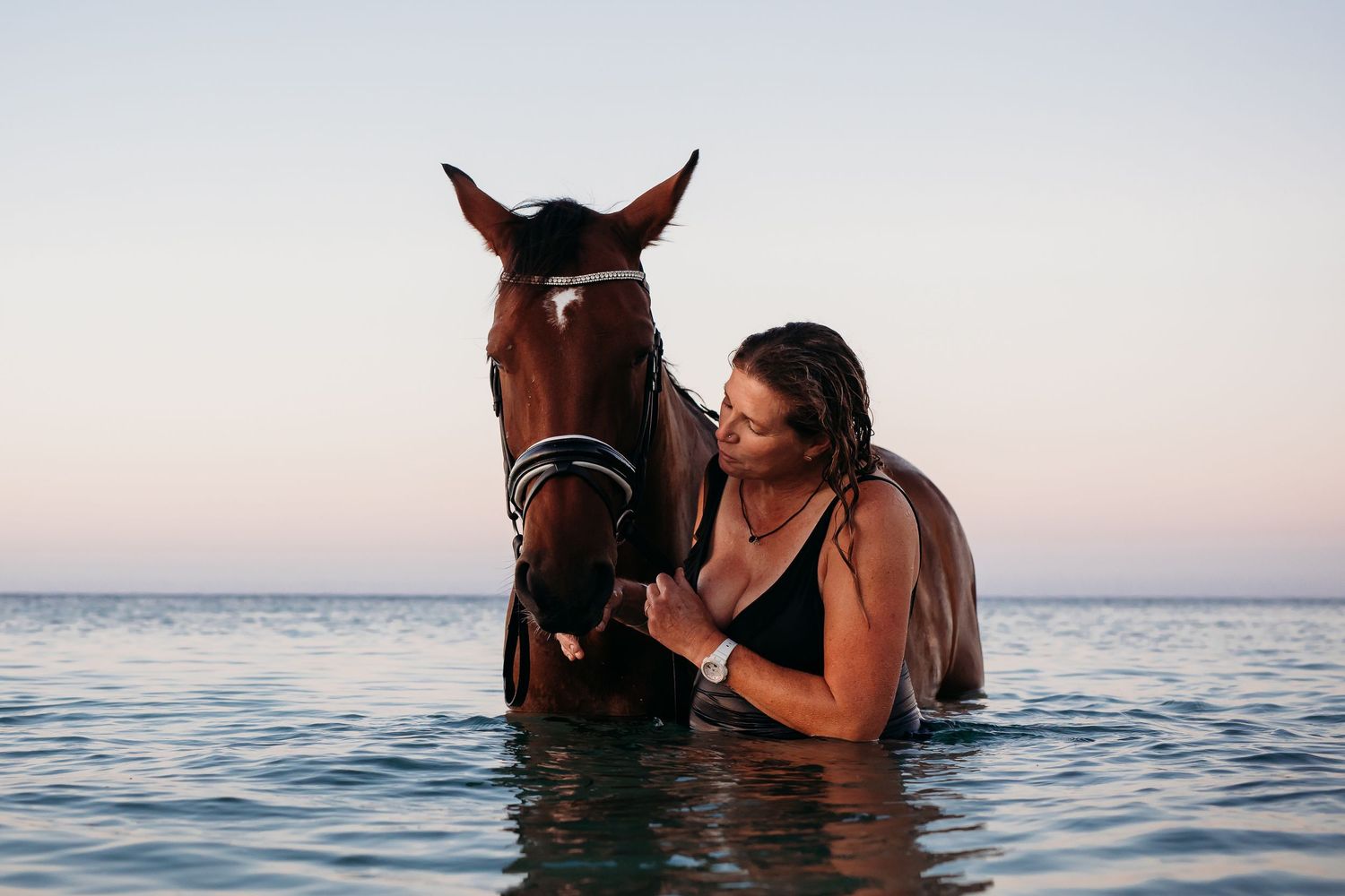 Lady standing in the ocean holding her horse. Adelaide, South Australia.  Raised by Water Photography