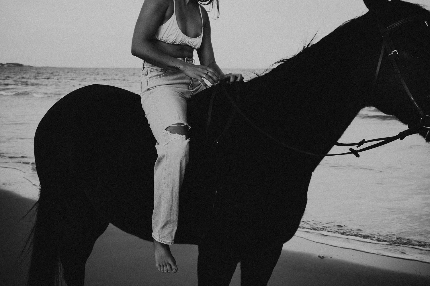 Candid photo of woman’s legs on horseback with ocean in background – Raised by Water Photography