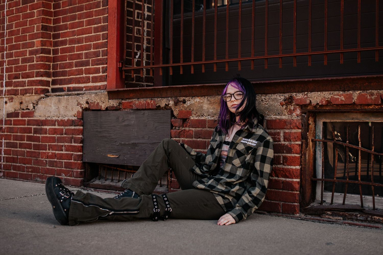 Moody portraits taken against red brick wall with iron gate details.