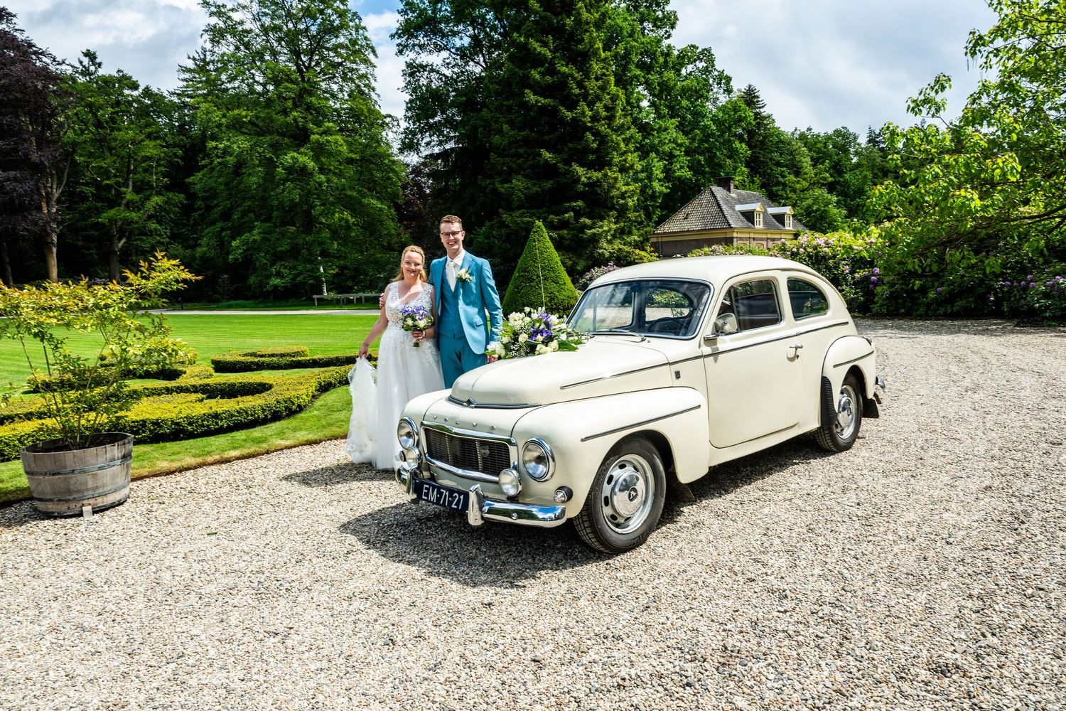 A classic white vintage car parked in a garden driveway.