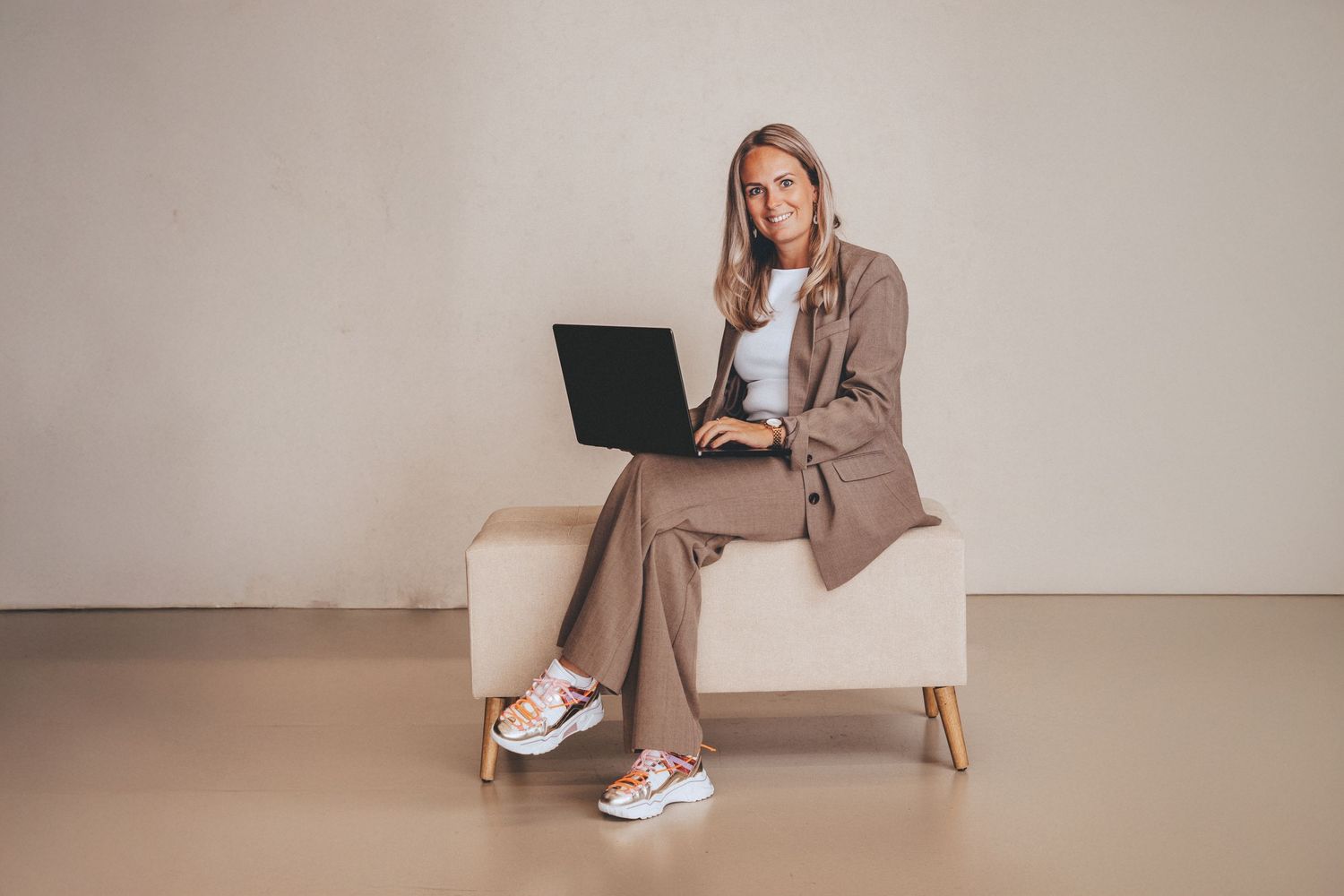 Modern lifestyle photoshoot featuring casual loungewear and sneakers against beige background.