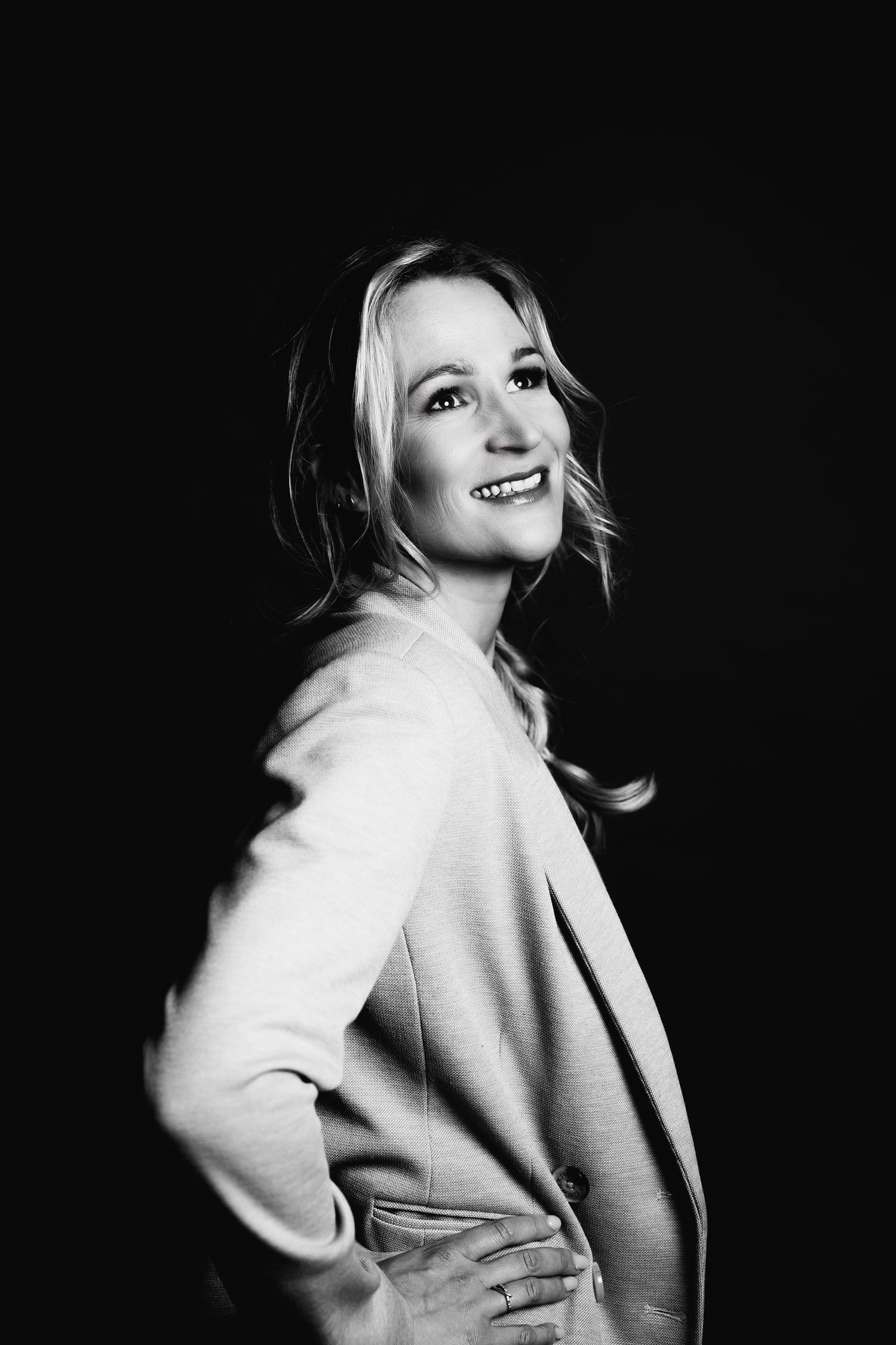 Black and white artistic portrait showing a joyful expression and light colored blazer.