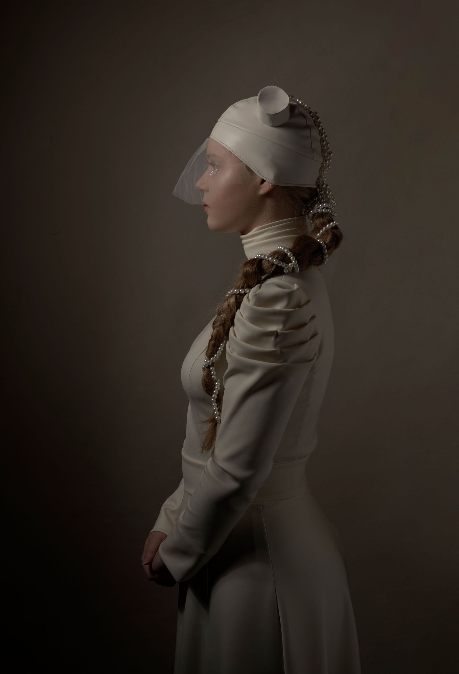 Figure in white winter clothing poses dramatically against dark background in artistic portrait series.