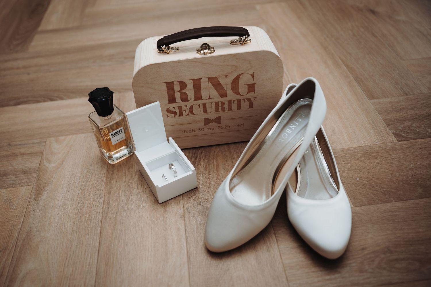 White bridal shoes and wedding accessories arranged on wooden flooring.