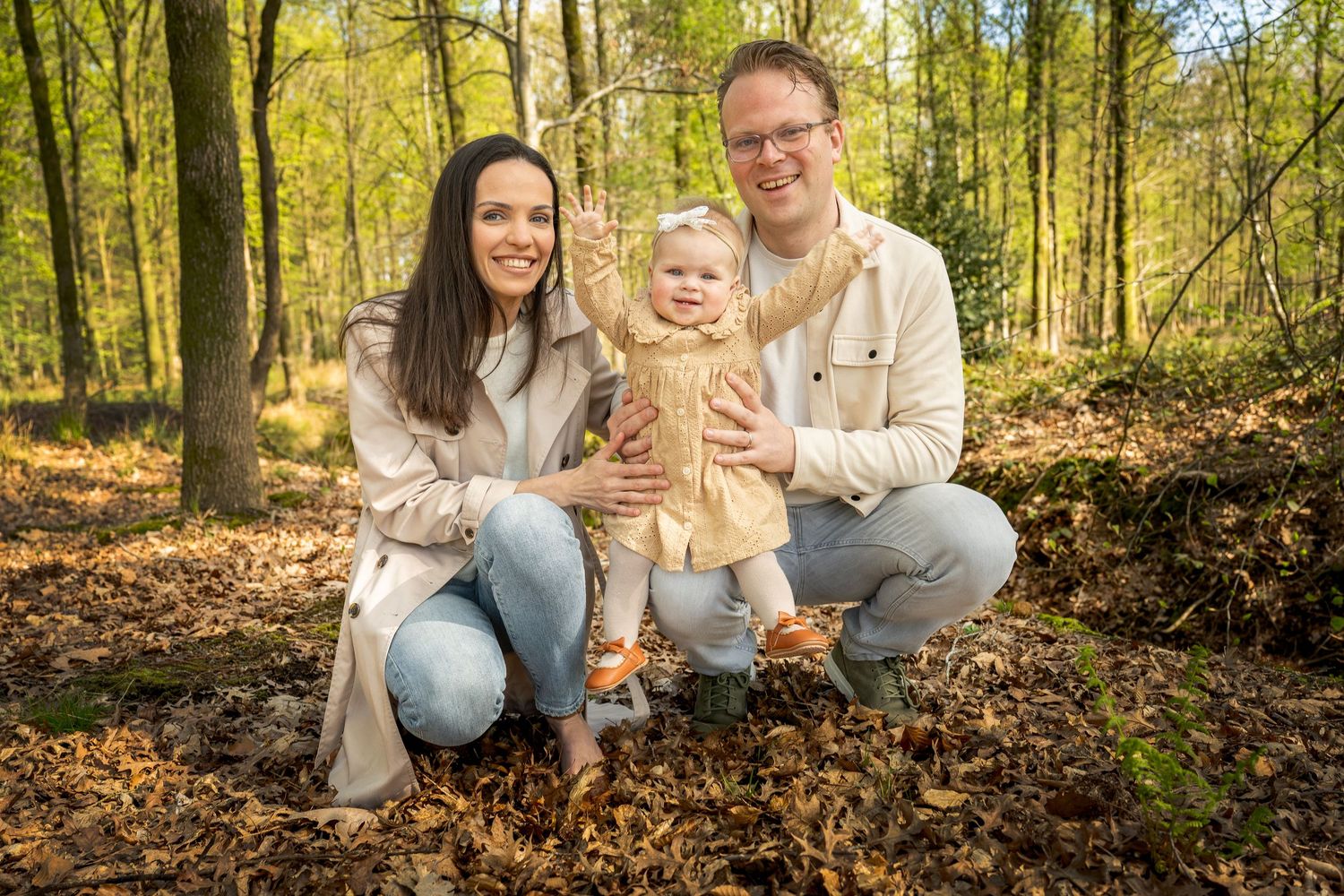 Family poses together during autumn photoshoot in sunlit forest setting.