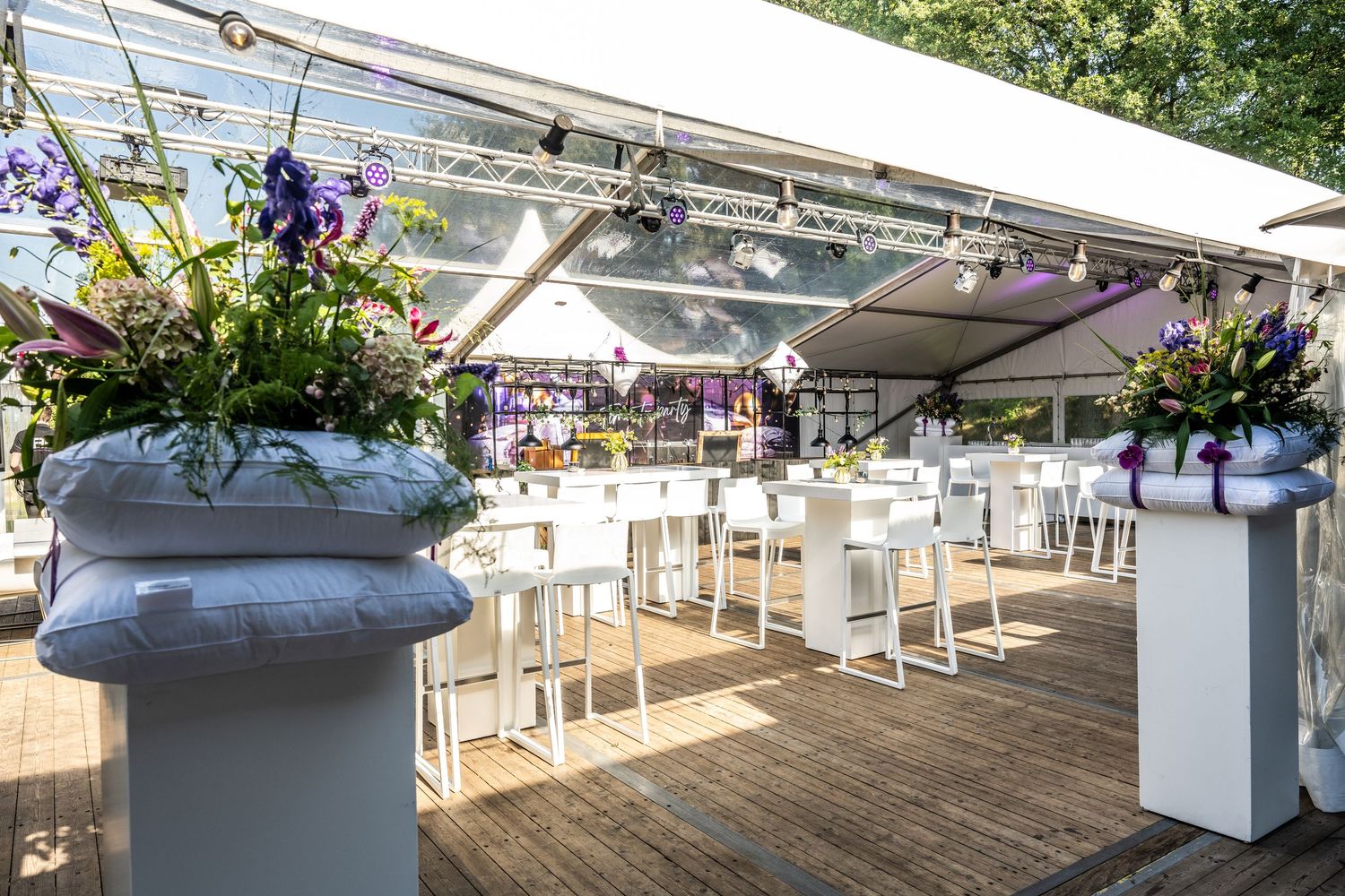 Elegant outdoor dining area with white tables and chairs set up under a covered patio space.