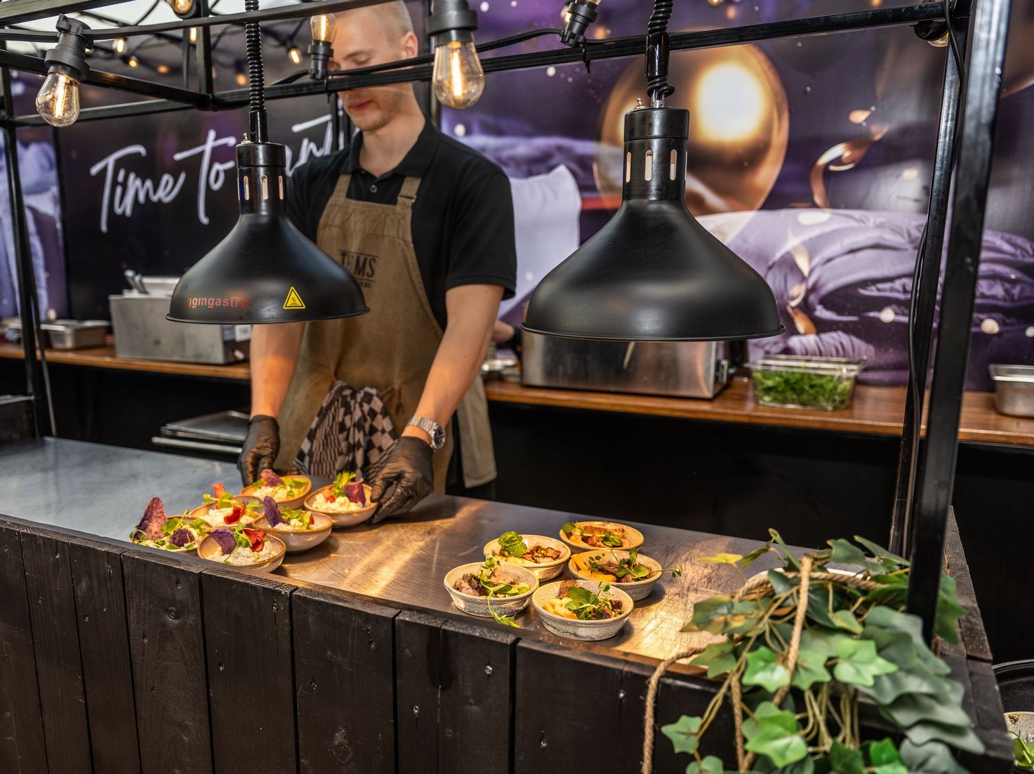 Restaurant kitchen staff preparing food at a rustic wooden counter with fresh ingredients and cooking equipment.