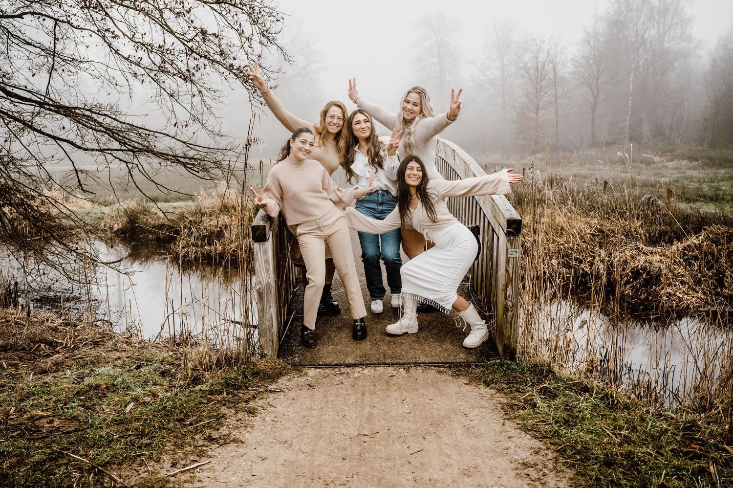 Outdoor family photography session by a misty pond with people in coordinated casual attire.