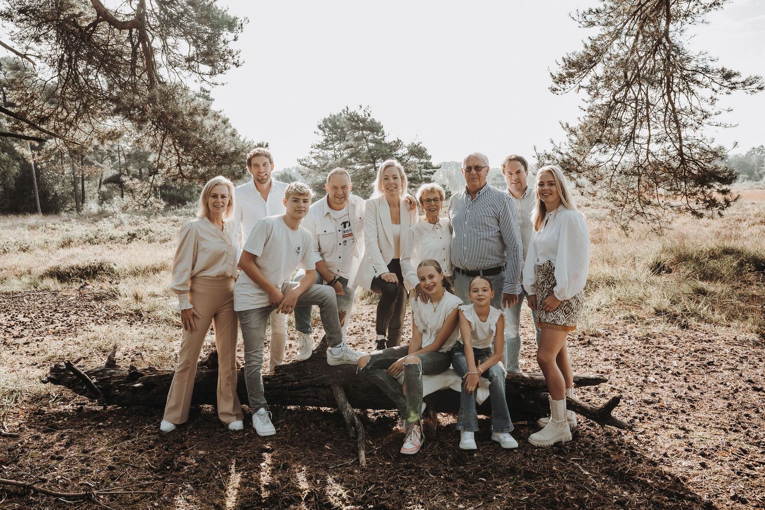 Extended family photo session in a natural outdoor setting with everyone wearing light neutral colors.