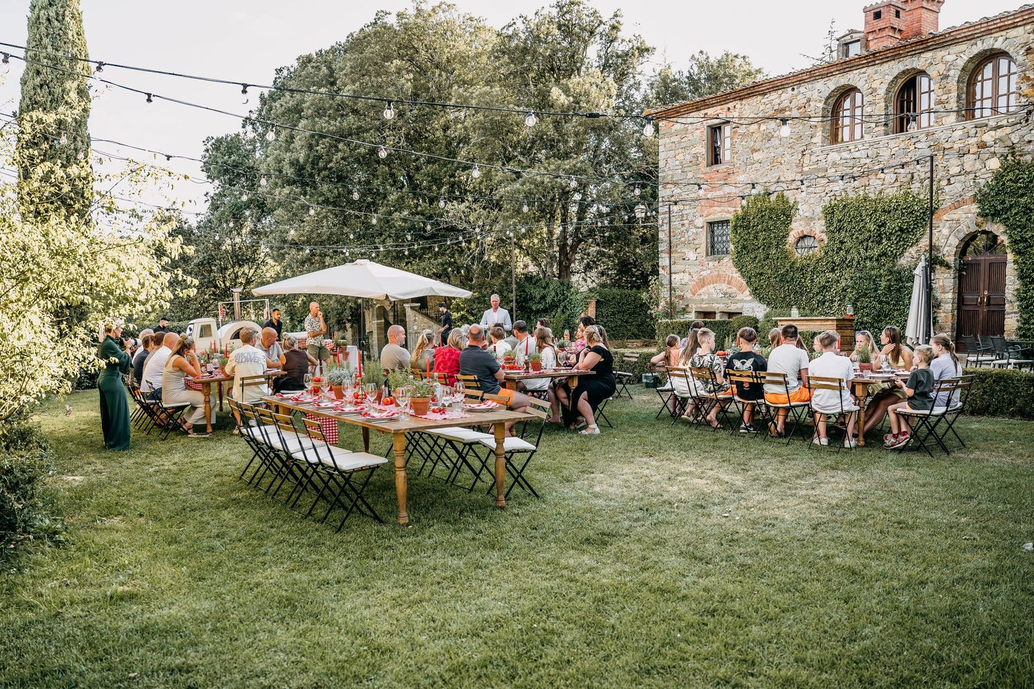 Outdoor wedding reception setup in a rustic garden setting with long tables.
