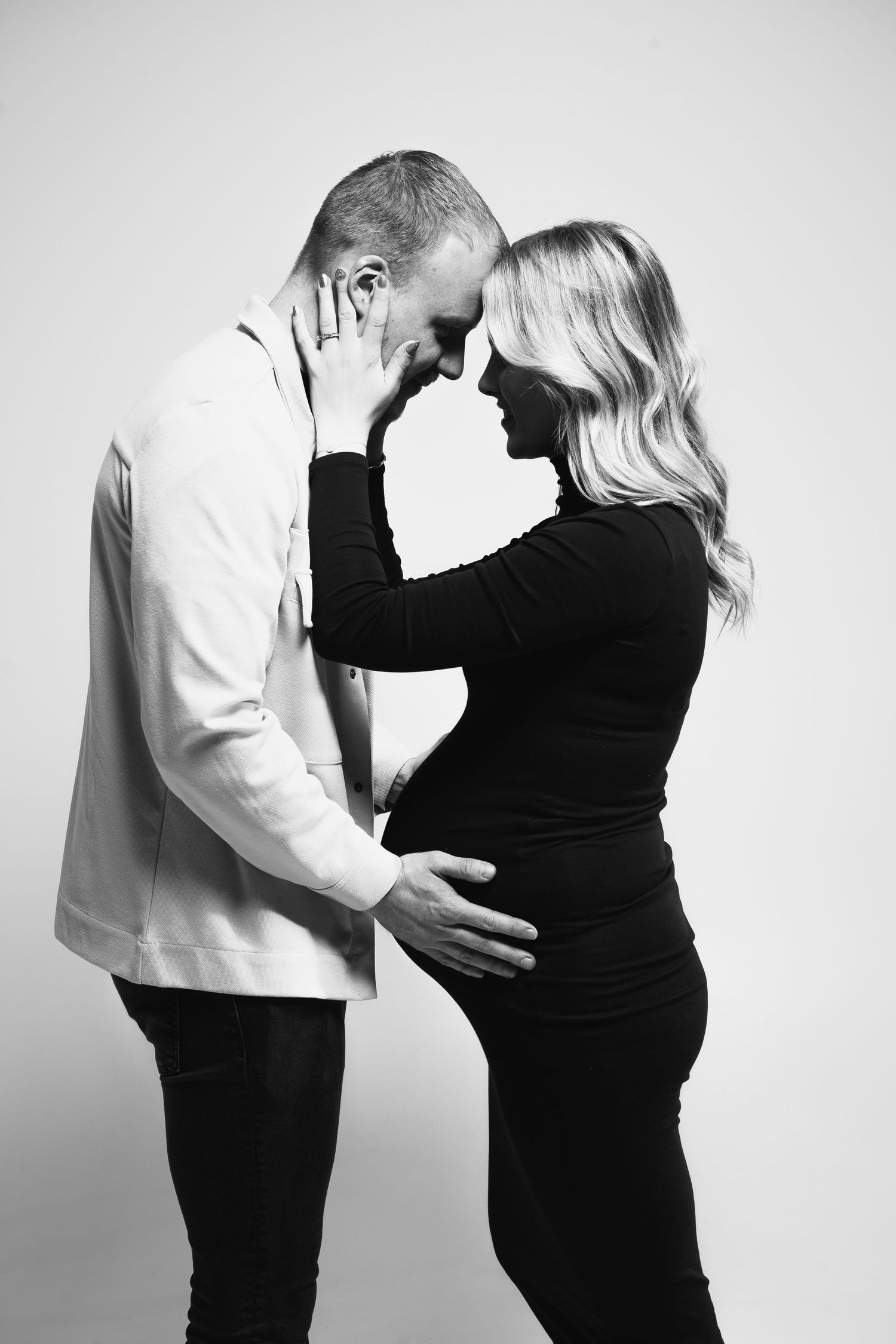 Black and white maternity photo series showing tender moments between expectant parents in silhouette.