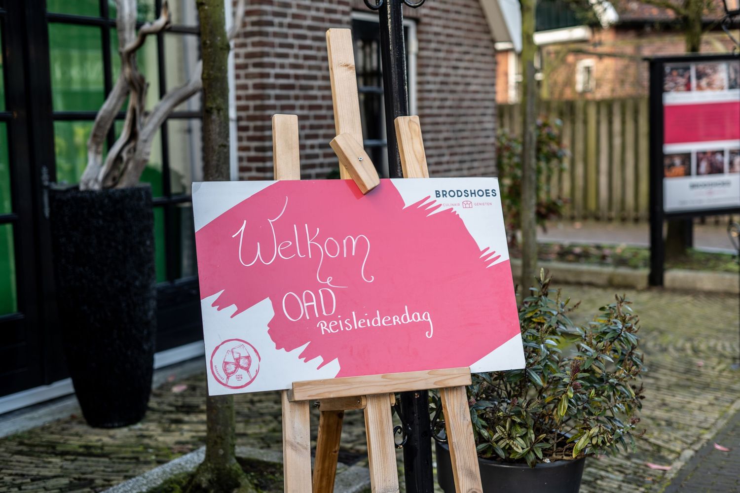 Pink directional signs mounted on wooden posts against a brick wall.