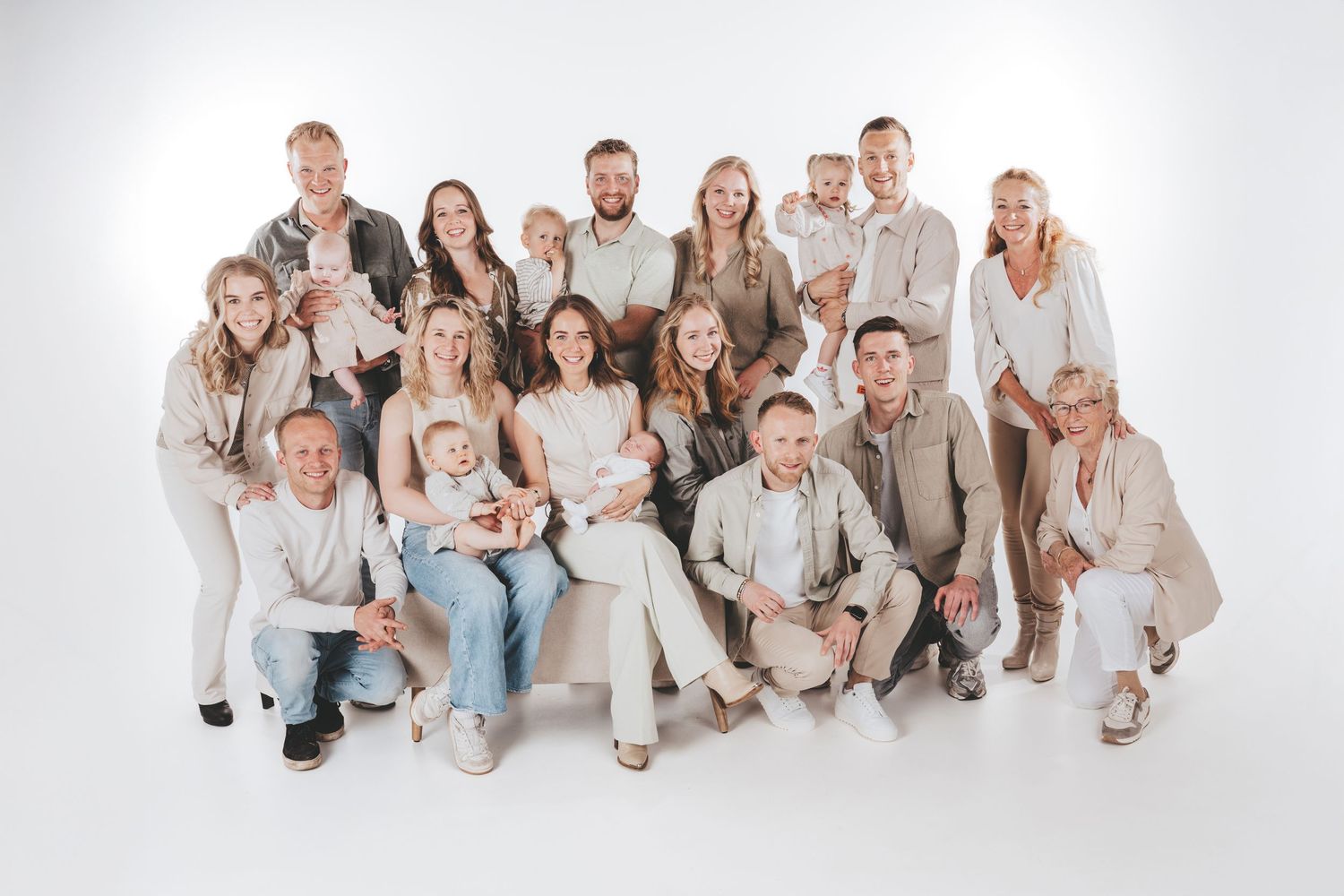 Large family group photo in coordinated white and beige outfits against white background.